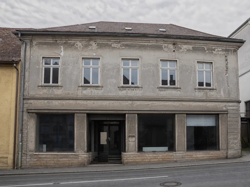 Verwitterte Gewerbefassade vor dem Anstrich: verblichener, rissiger Putz.