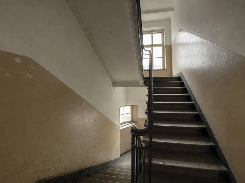 Treppenhaus vor der Renovierung: verschmutzte, abgeplatzte Wände.